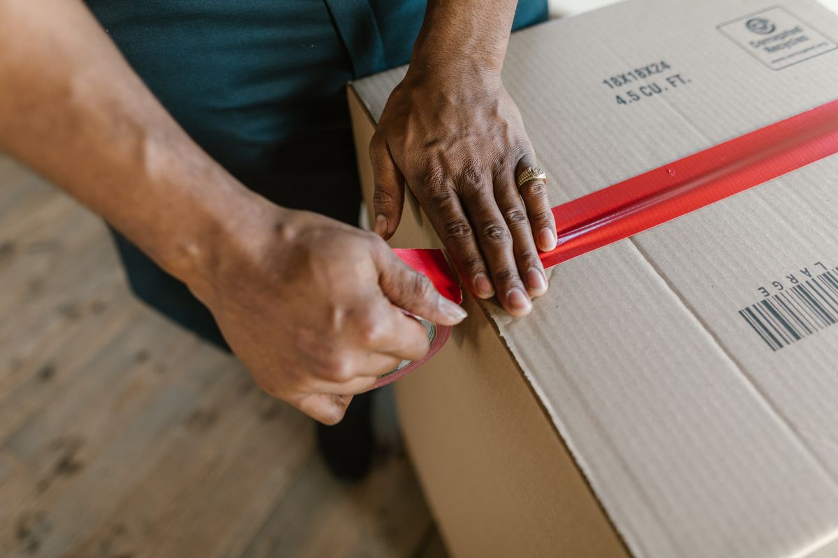 Packing worker sealing a carton with a tape dispenser